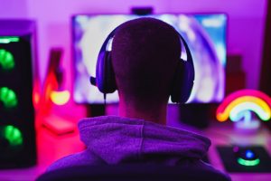 Young man wearing headset and play computer video games online - Home isolated for coronavirus outbreak